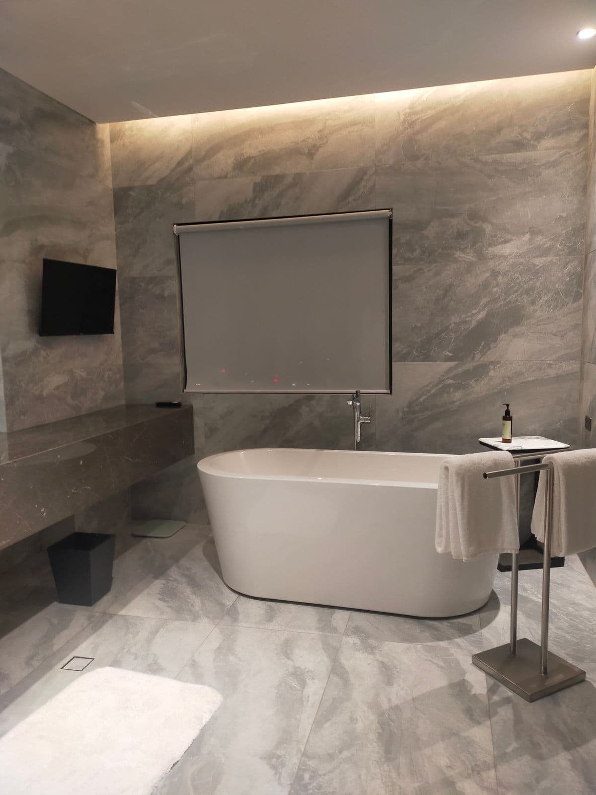 Primary bathroom with a freestanding tub and large-format tile