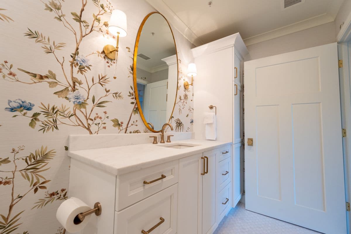 Powder room with botanical wallpaper, brass fixtures, and a marble-top vanity