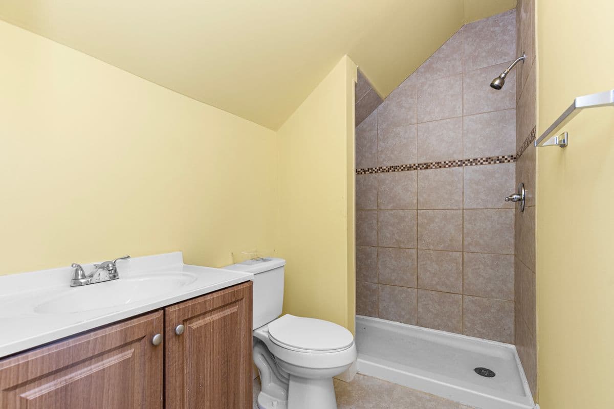 Renovated bathroom with a wood vanity and a tiled corner shower stall