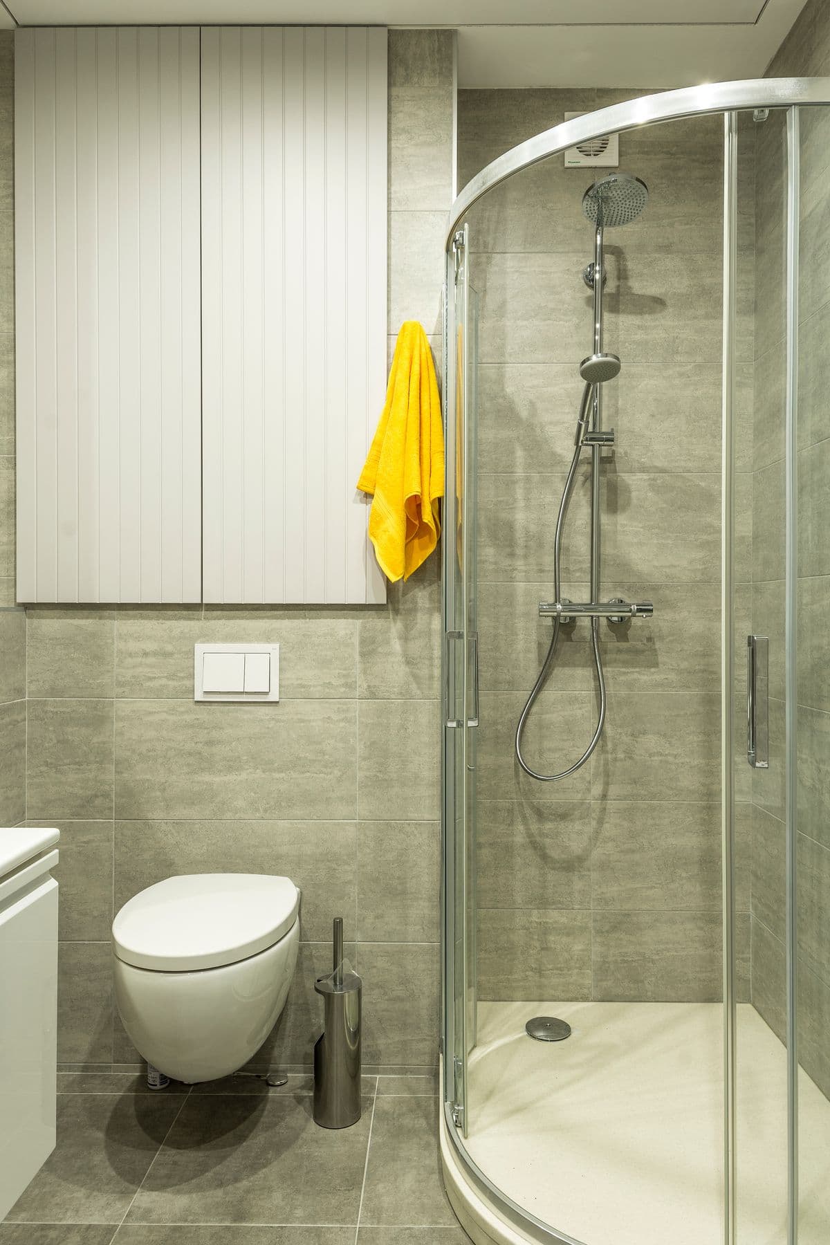 Small renovated bathroom with a tiled corner shower and wall-mounted cabinet