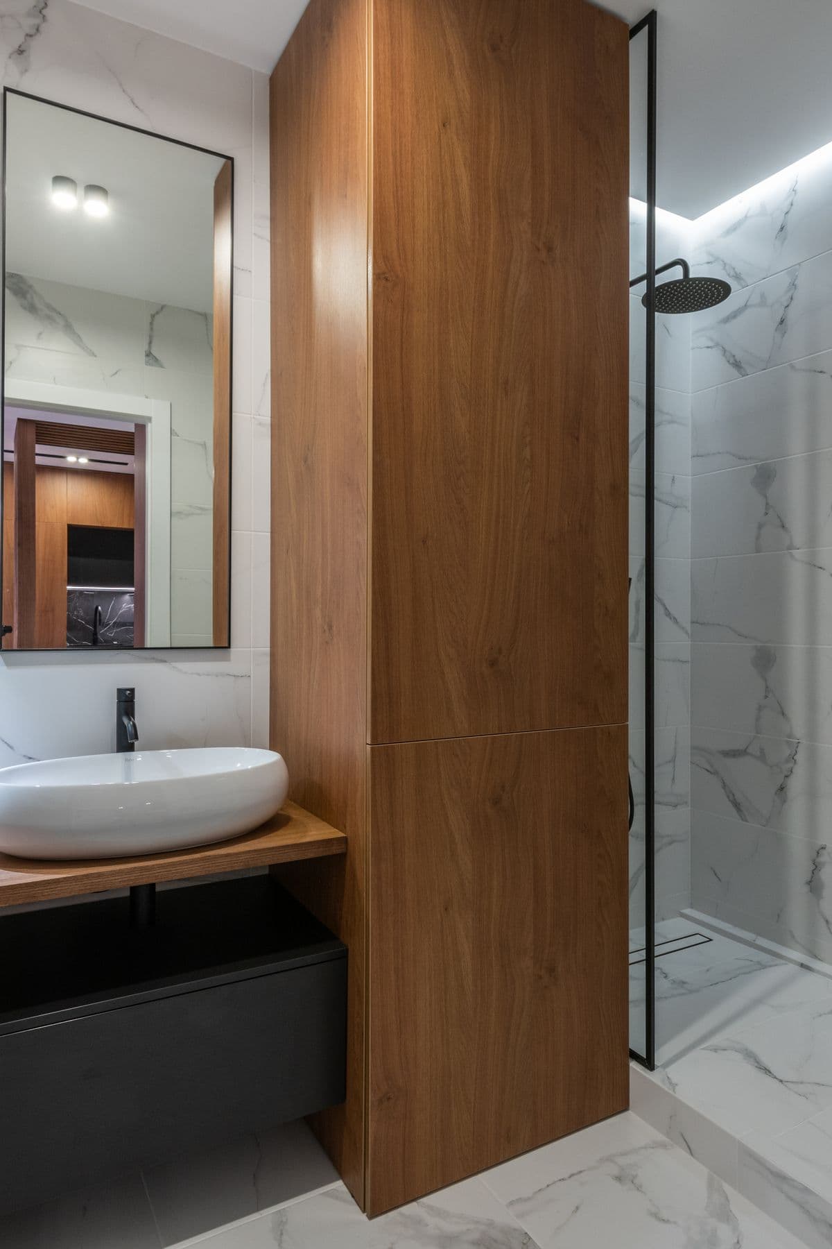 Minimalist bathroom with white walls, wood-tone vanity and matte fixtures