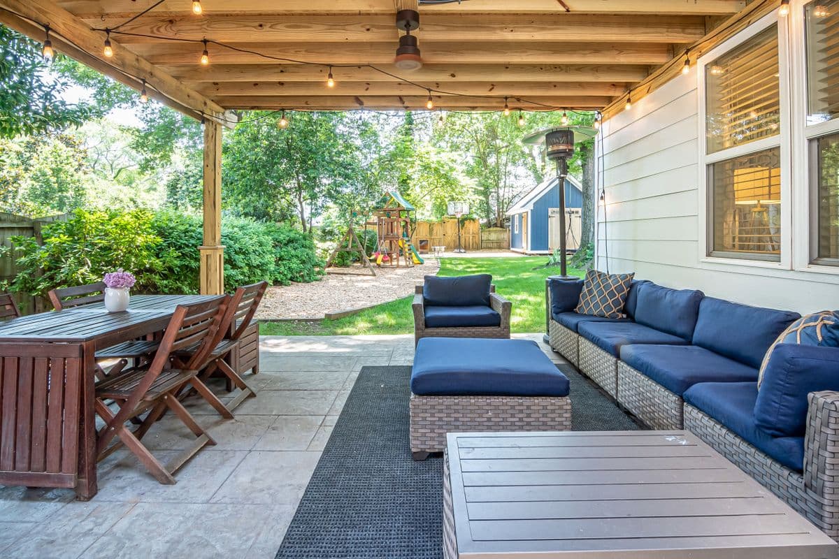 Covered back patio with a sectional sofa, dining table, and string lights