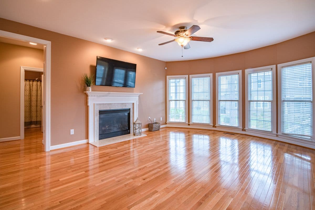 Glossy hardwood flooring installed in a living room with a fireplace and ceiling fan
