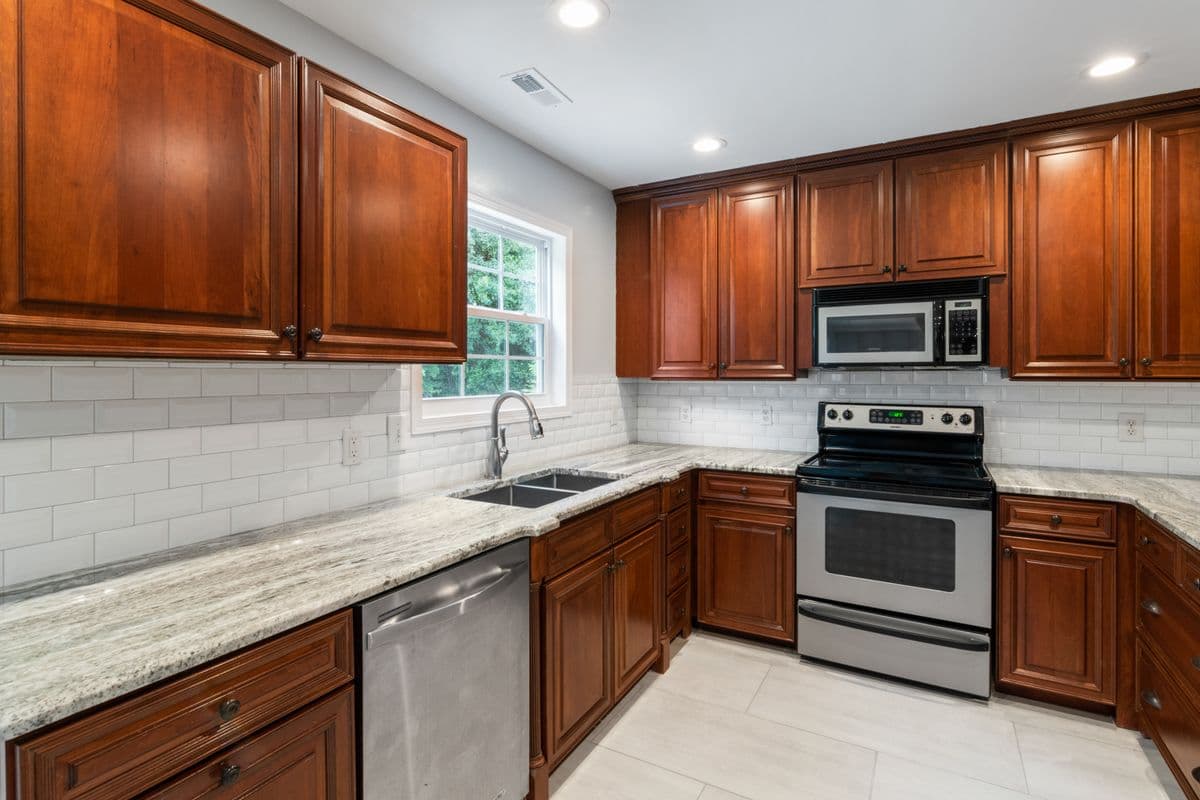 Cherry cabinet kitchen with granite countertops and a subway tile backsplash
