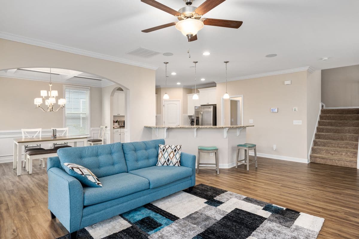 Open living room with a blue sofa facing an updated kitchen island and dining nook