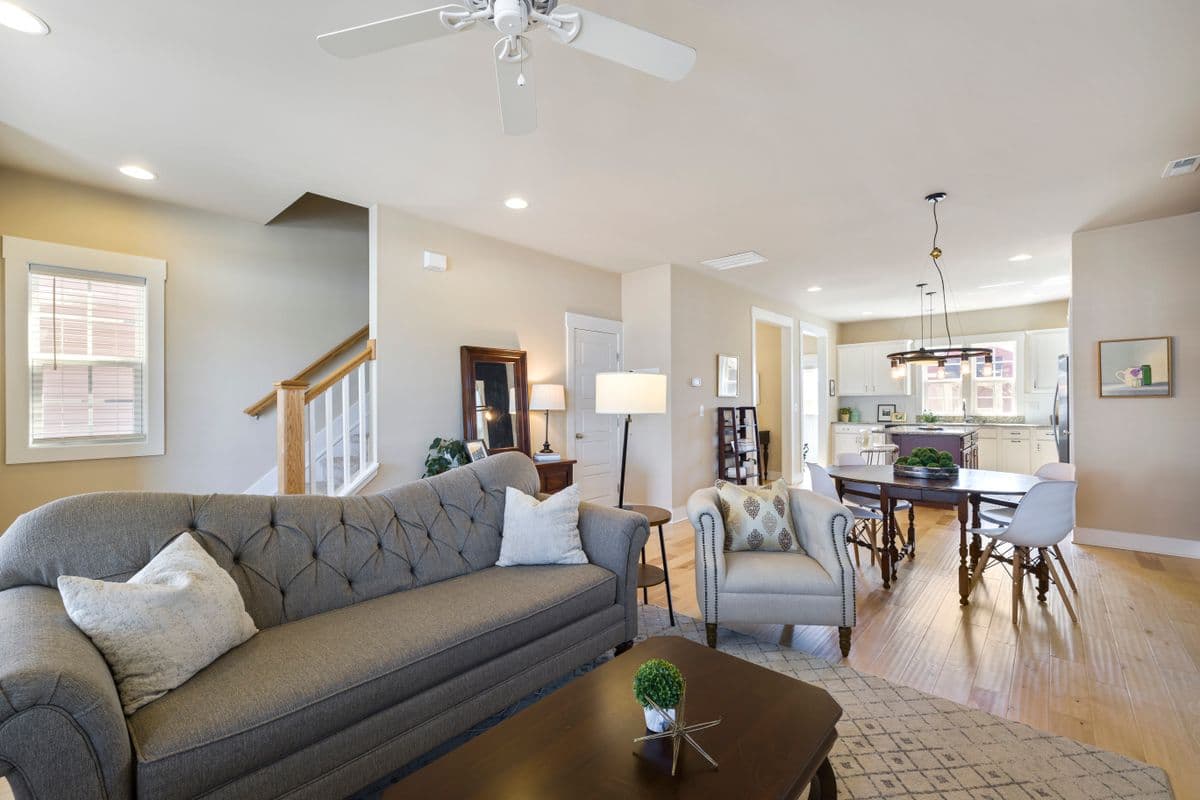 Renovated living room with new flooring, staircase trim, and an open kitchen beyond