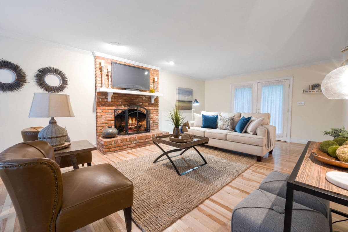 Renovated family room with a brick fireplace, wood floors, and new trim