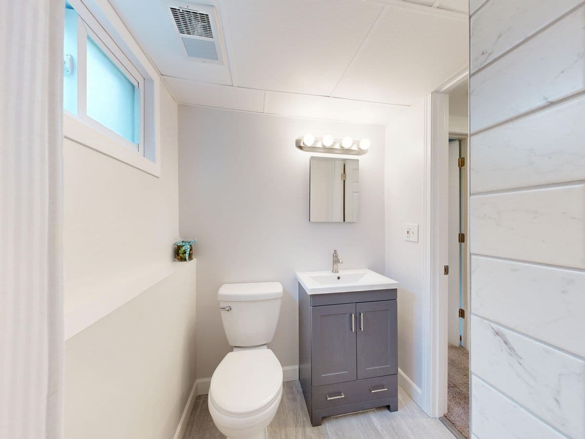 Compact renovated bathroom with a wood-tone vanity and gray plank flooring