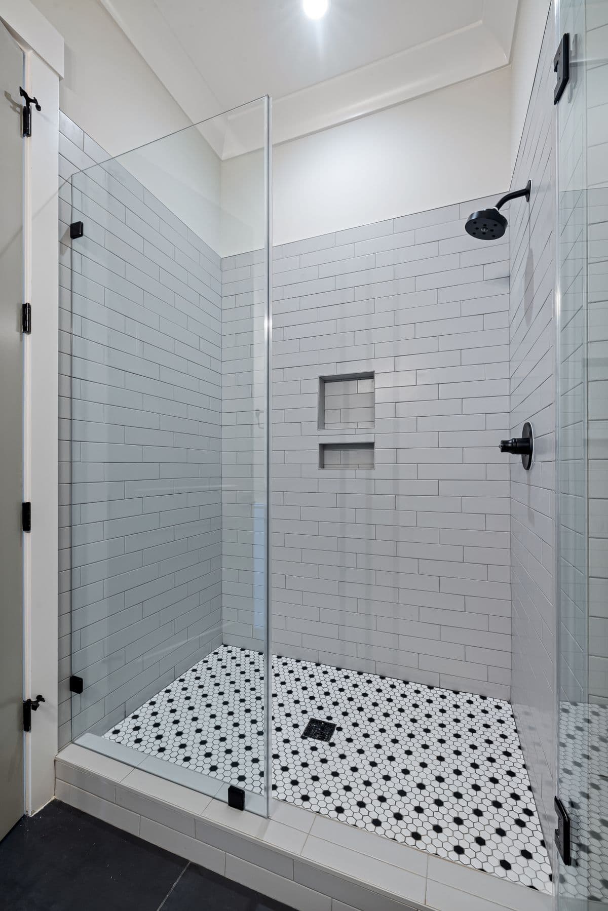 Glass-enclosed walk-in shower with subway tile walls and a built-in tiled niche