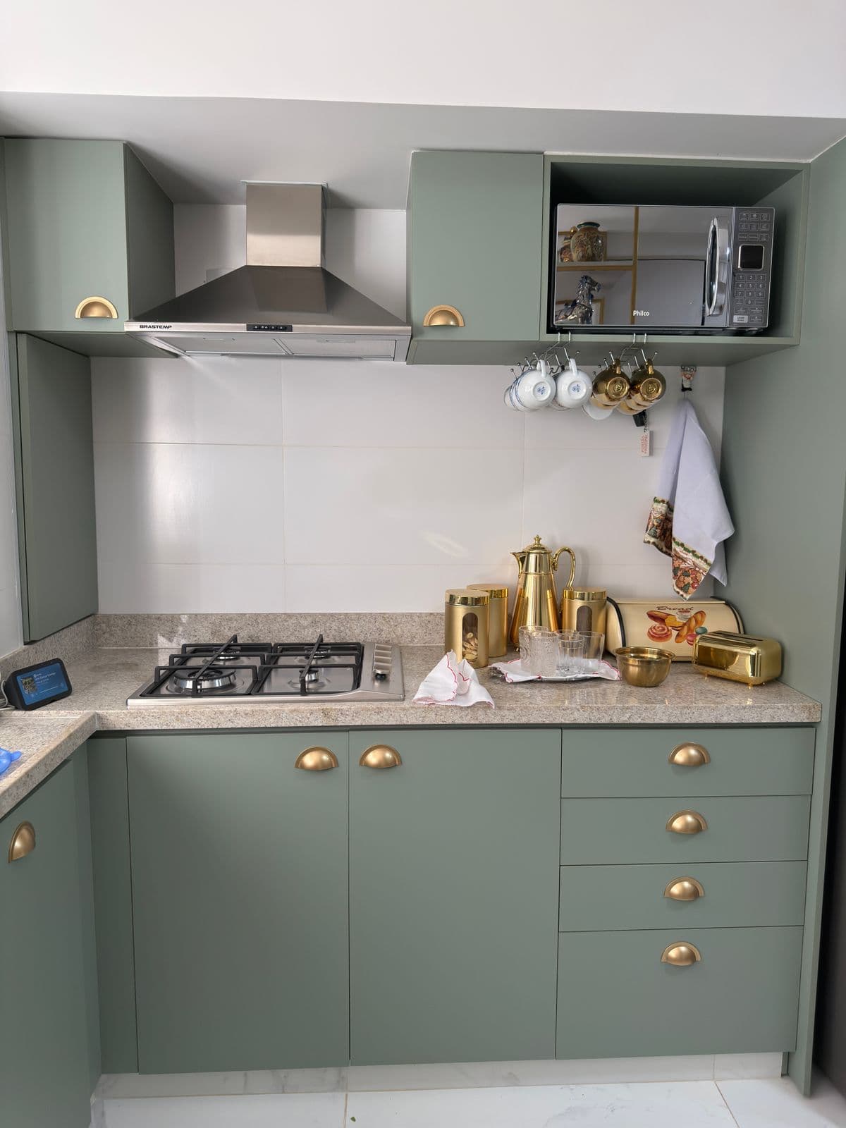 Sage green shaker kitchen with unlacquered brass hardware and marble countertops