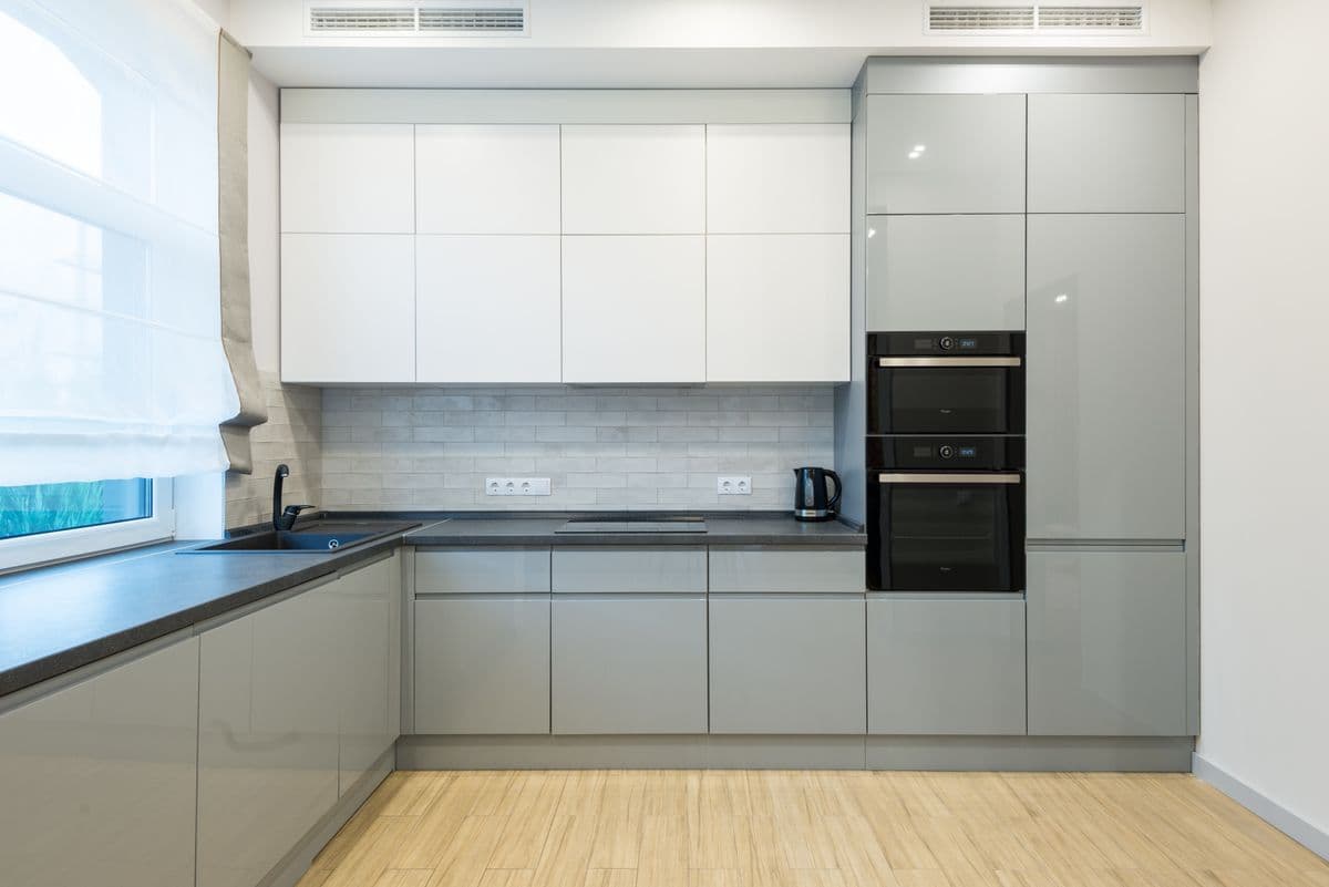 Two-tone kitchen with high-gloss white upper cabinets and sage lower cabinetry